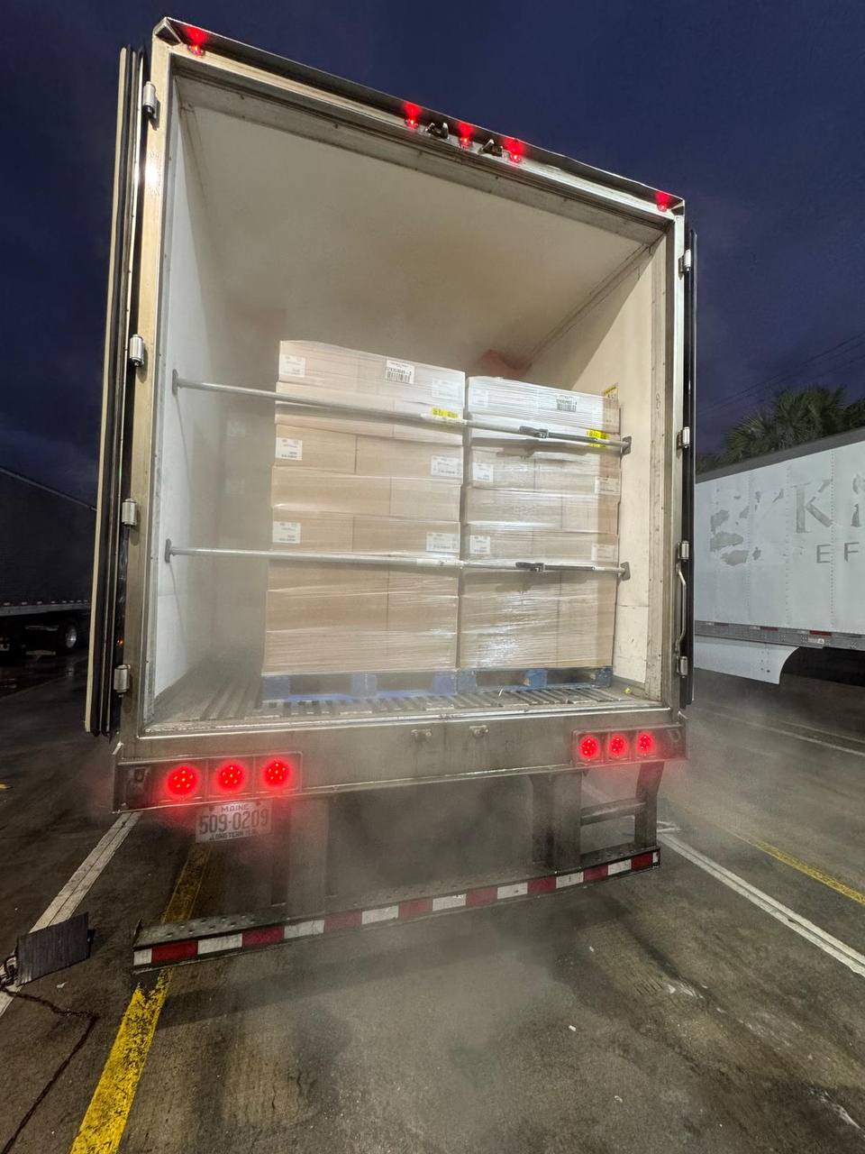 Refrigerated trailer loaded with palletized, shrink-wrapped freight braced by load bars